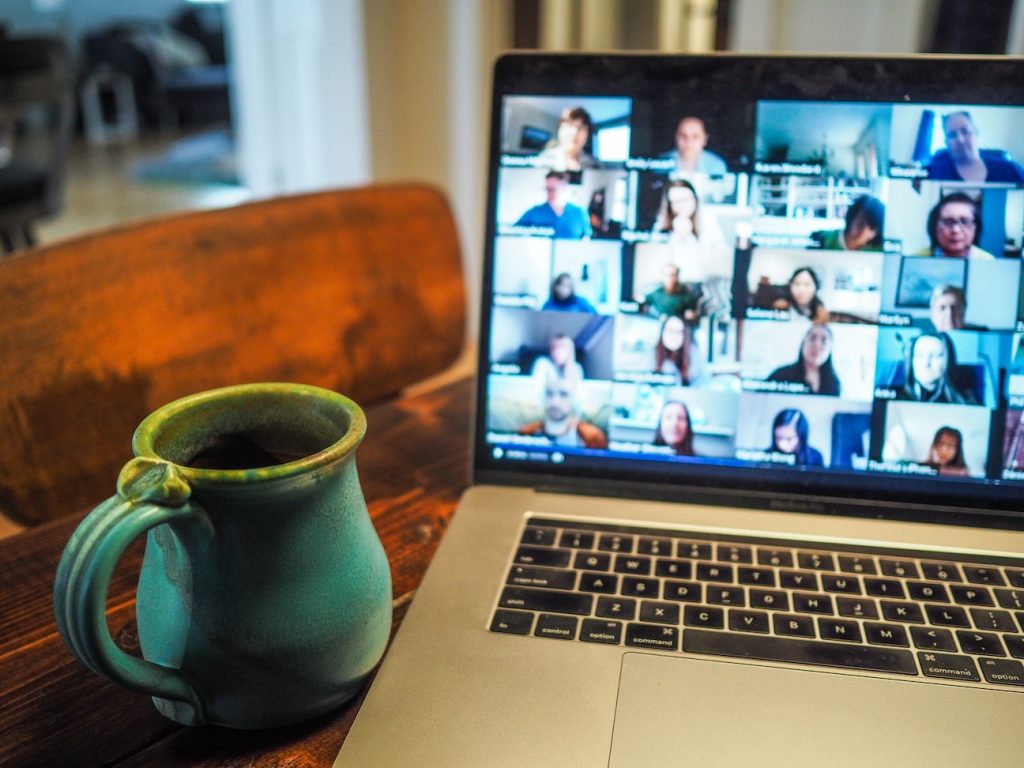 a green cup and a video conference call on screen of a laptop