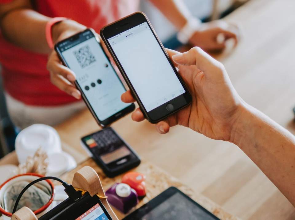 two person's hands holding a turned-on mobile phone
