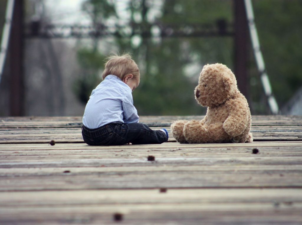 young boy sitting with a large teddy bear